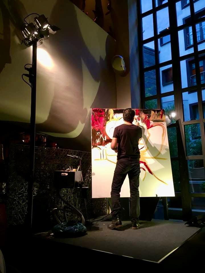 Painting on a lit stage at night, the canvas the brightest thing in the room